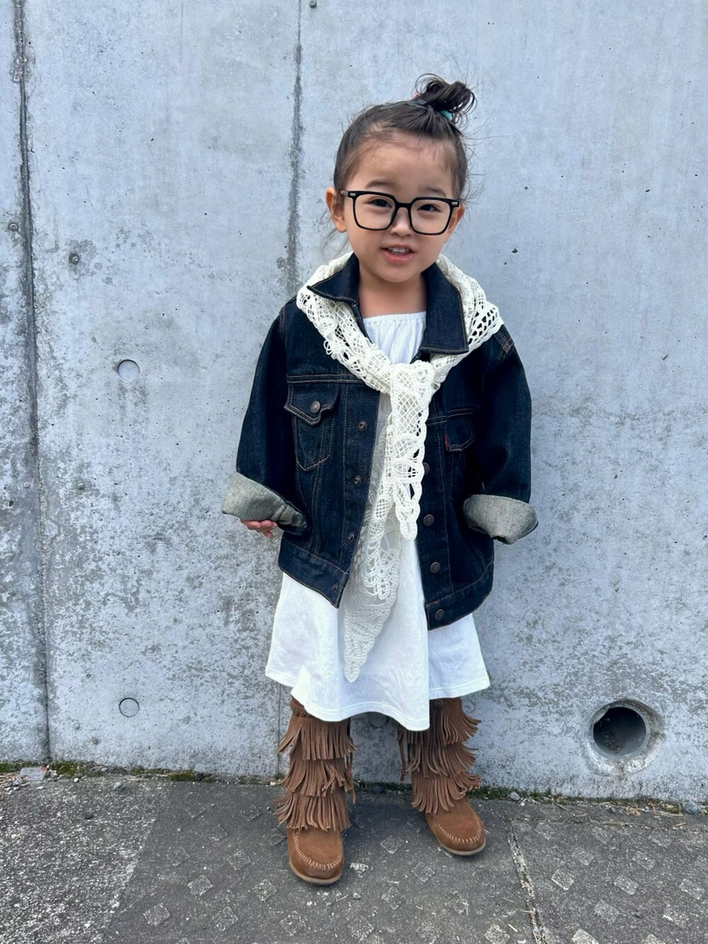 ブルー系のデニムジャケット、ホワイト系のワンピース/ドレス、ブラウン系のブーツを着用したキッズの春コーディネートの2枚目の写真