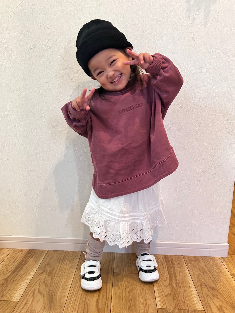 パープル系のスウェット、ホワイト系のスカート、ホワイト系のスニーカーを着用したキッズの秋コーディネートの2枚目の写真