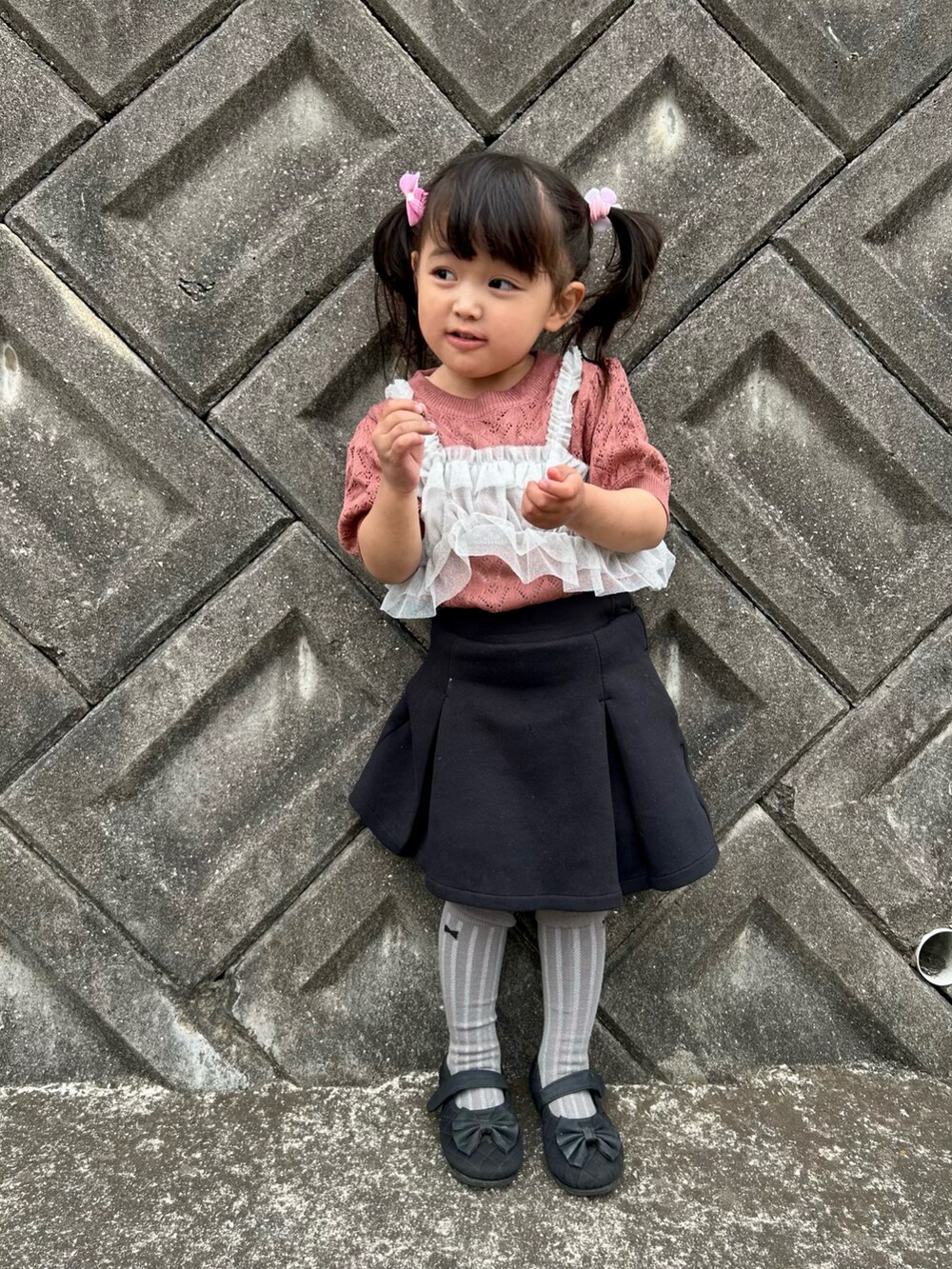 ピンク系のニット/セーター、ブラック系のスカートを着用したキッズの春コーディネートの2枚目の写真