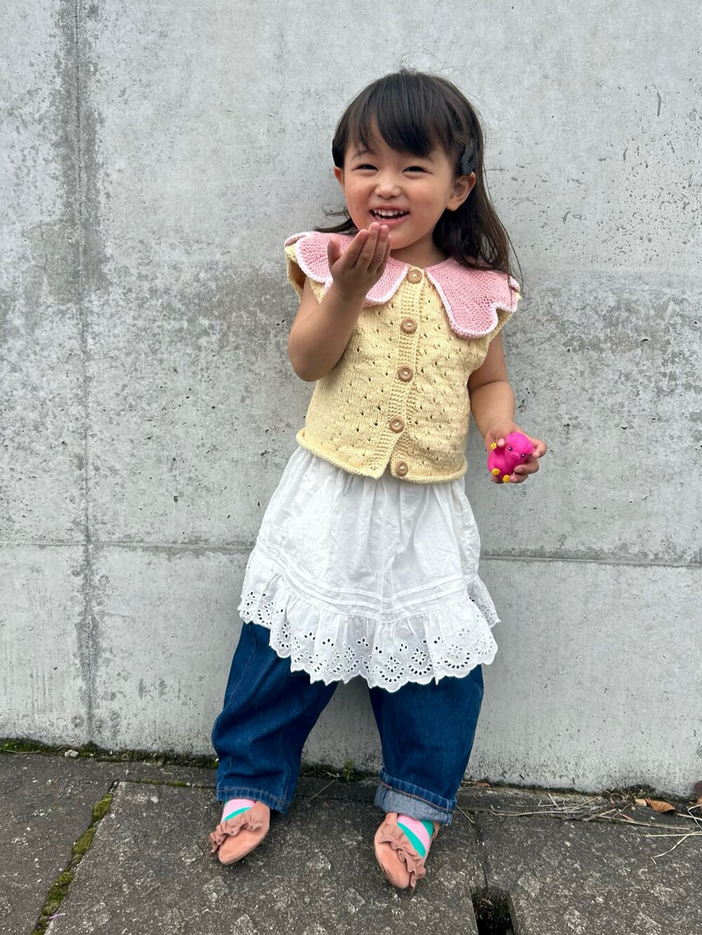 イエロー系のベスト、ホワイト系のスカート、ブルー系のデニムパンツを着用したキッズの春コーディネートの2枚目の写真