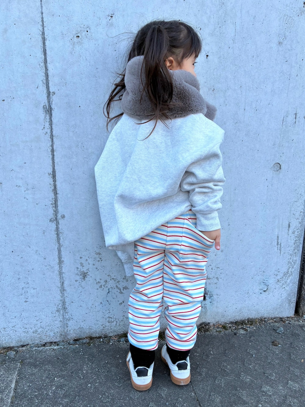 グレー系のスウェット、ベージュ系のマフラー、ブルー系のレギンス/スパッツを着用したキッズの冬コーディネートの3枚目の写真