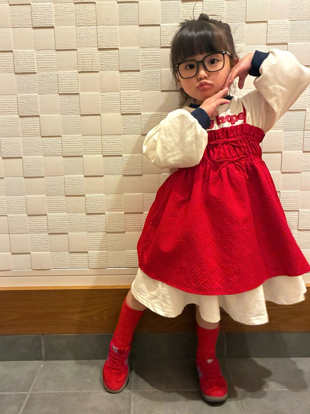 ベージュ系のワンピース、レッド系のキャミソール、レッド系のスニーカーを着用したキッズの春コーディネートの2枚目の写真