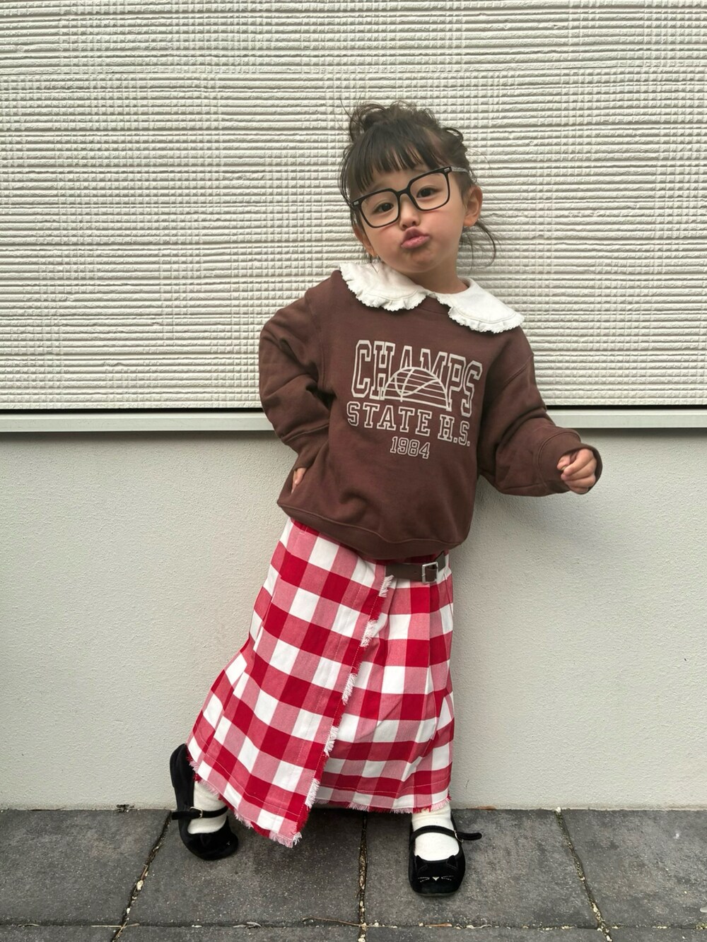 ブラウン系のスウェット、レッド系のスカート、ホワイト系のトップスを着用したキッズの冬コーディネートの2枚目の写真