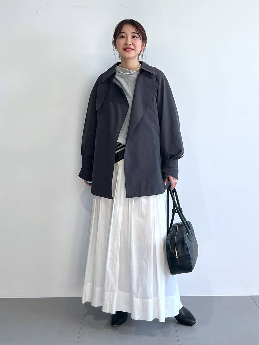 ホワイト系のスカート、グレー系のスウェット、グレー系のトレンチコートを着用したレディースの冬コーディネートの7枚目の写真