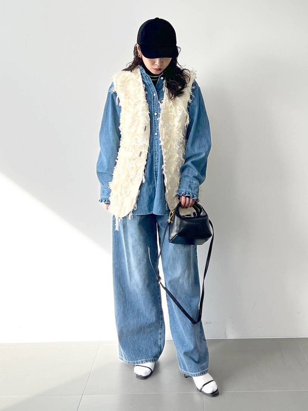 ブルー系のデニムパンツ、ブラック系のサンダル、ブラック系のTシャツ/カットソーを着用したレディースの冬コーディネートの5枚目の写真
