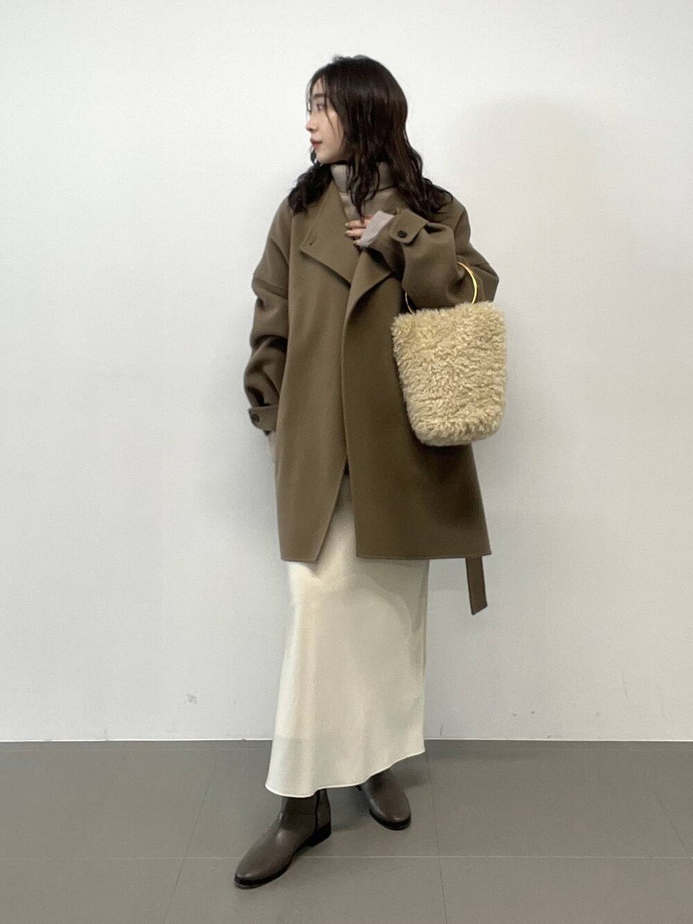 ホワイト系のハンドバッグ、ベージュ系のニット/セーター、グリーン系のピーコートを着用したレディースの秋コーディネートの4枚目の写真
