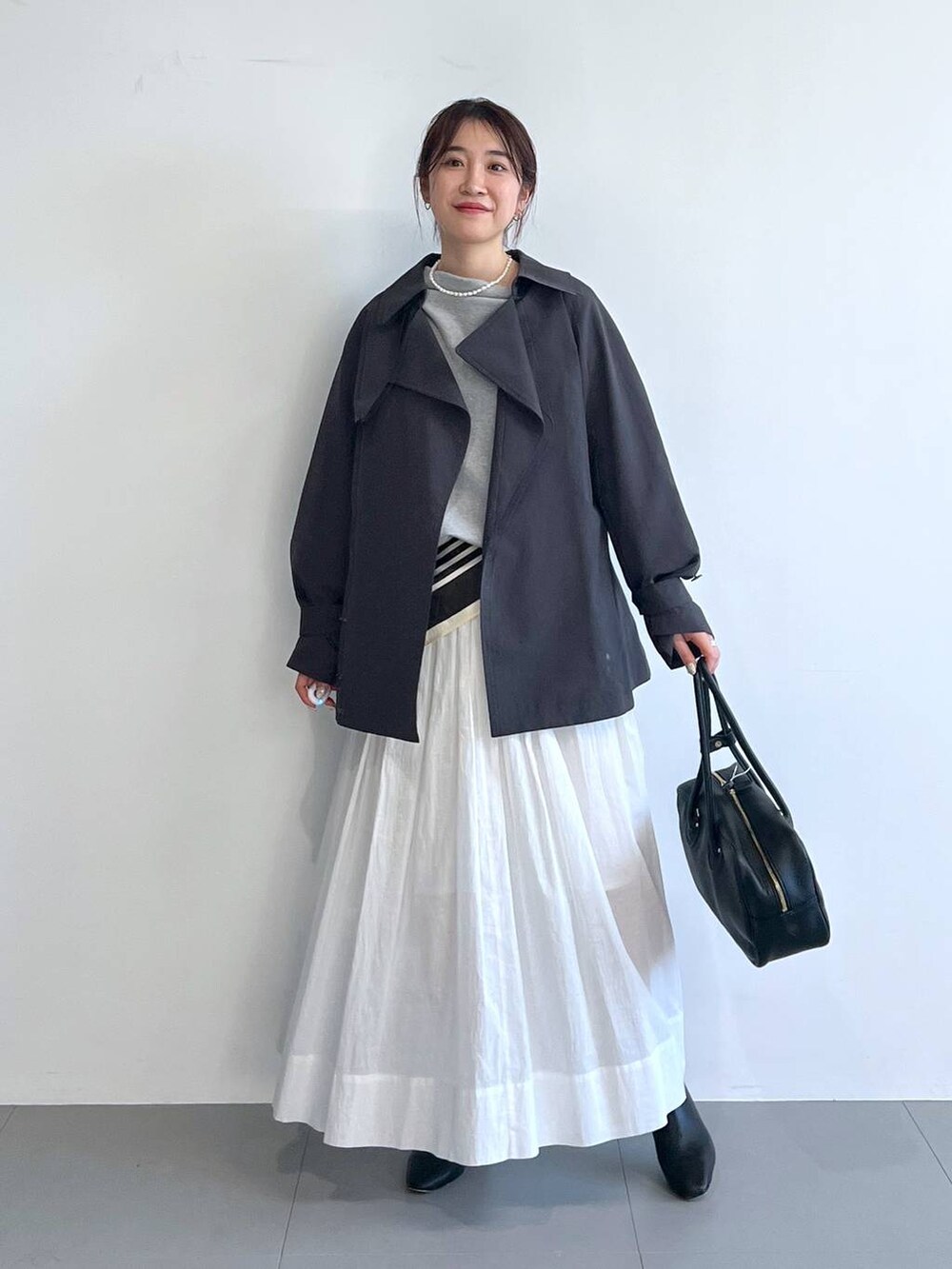 ホワイト系のスカート、グレー系のスウェット、グレー系のトレンチコートを着用したレディースの冬コーディネートの4枚目の写真