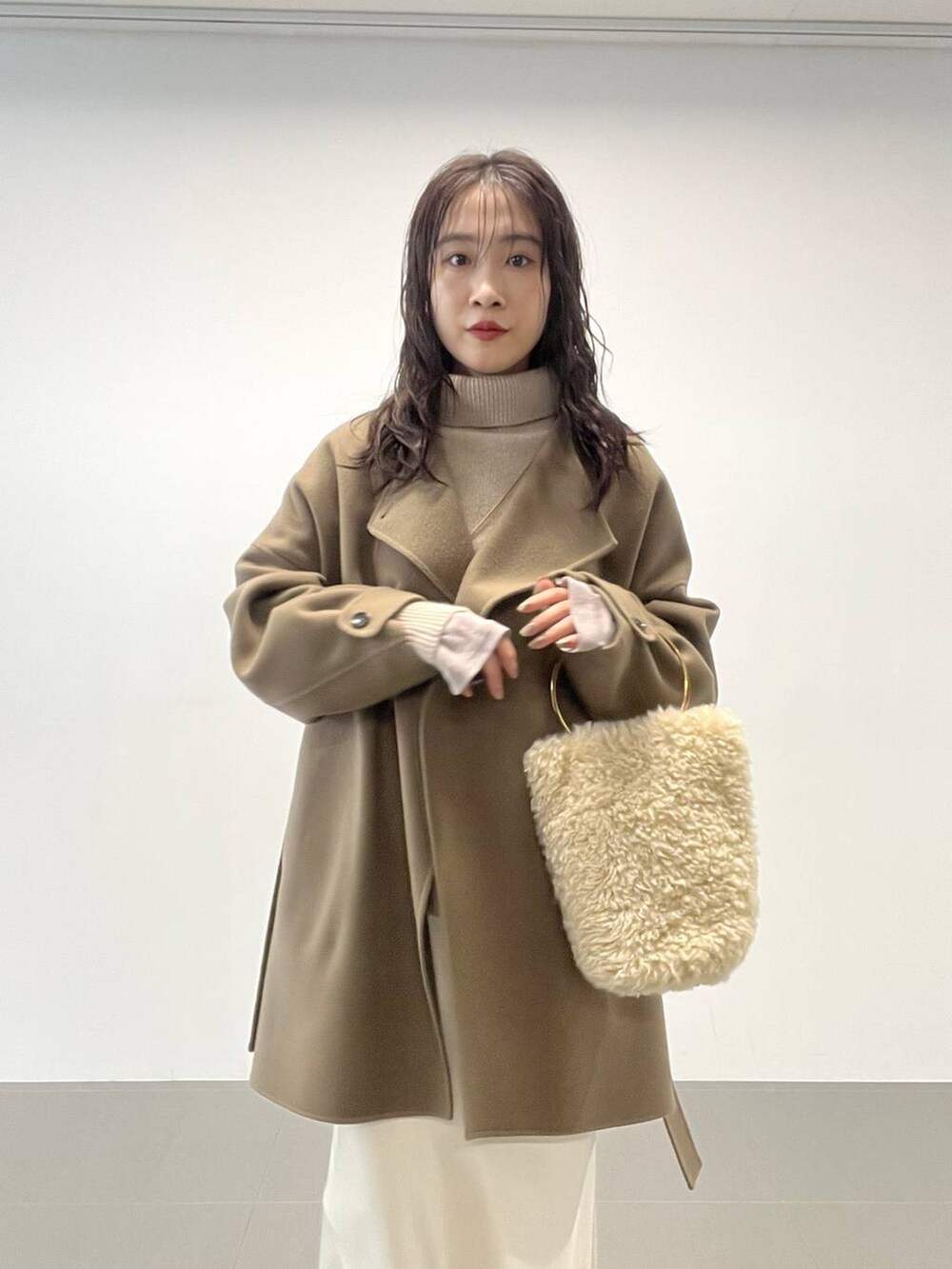 ホワイト系のハンドバッグ、ベージュ系のニット/セーター、グリーン系のピーコートを着用したレディースの秋コーディネートの6枚目の写真