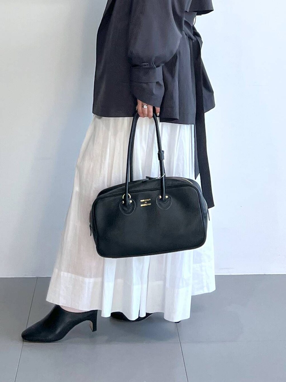 ホワイト系のスカート、グレー系のスウェット、グレー系のトレンチコートを着用したレディースの冬コーディネートの5枚目の写真