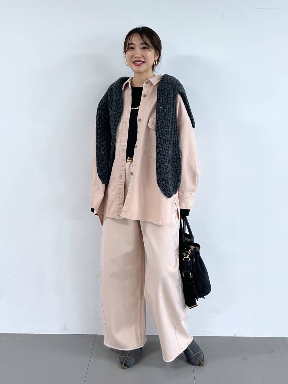 ピンク系のデニムパンツ、ベージュ系のサンダル、グレー系のニット/セーターを着用したレディースの冬コーディネートの2枚目の写真