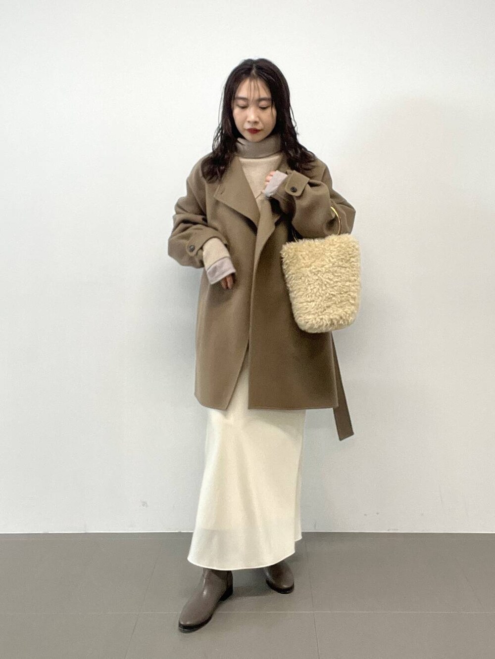 ホワイト系のハンドバッグ、ベージュ系のニット/セーター、グリーン系のピーコートを着用したレディースの秋コーディネートの3枚目の写真