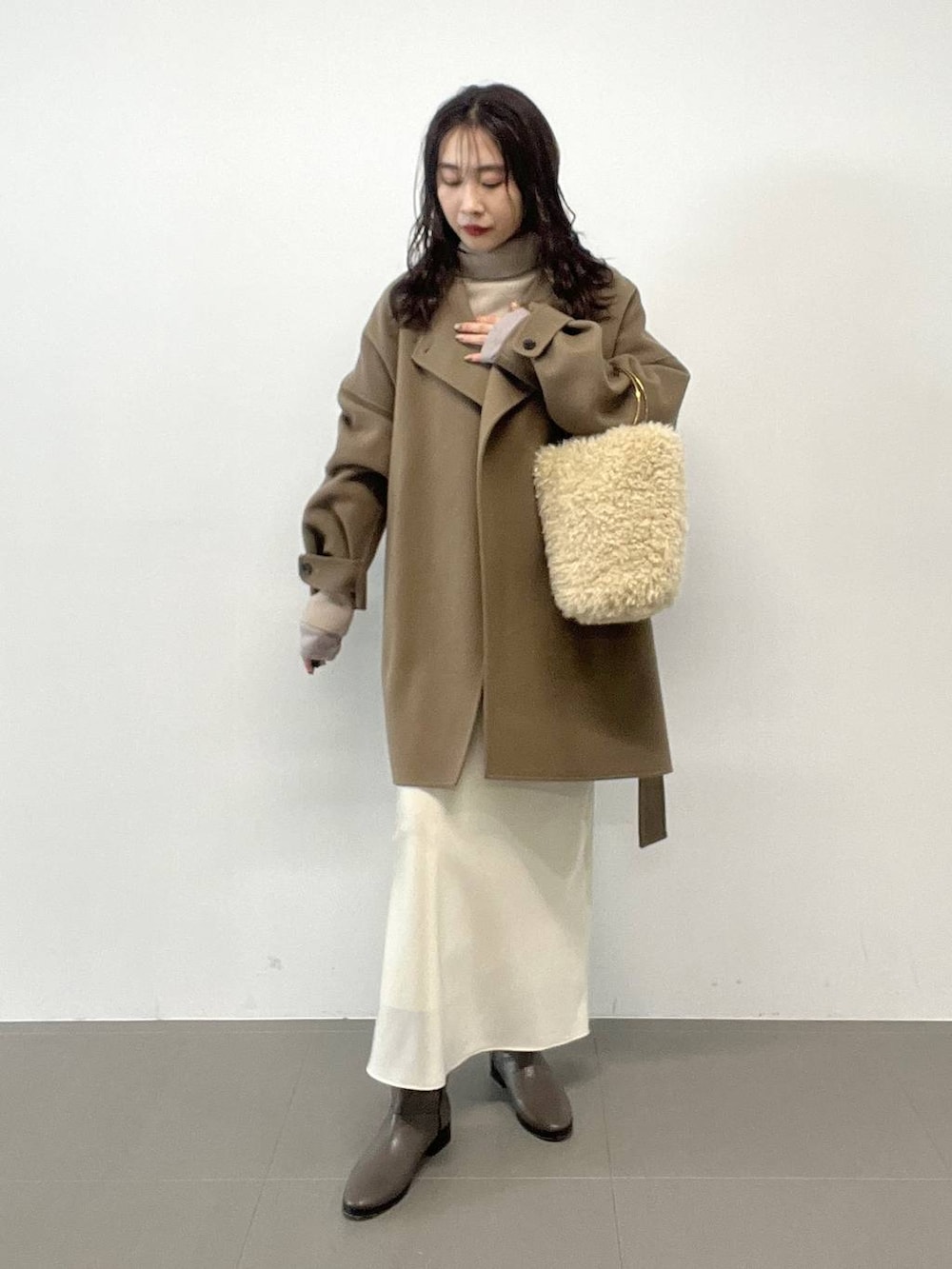 ホワイト系のハンドバッグ、ベージュ系のニット/セーター、グリーン系のピーコートを着用したレディースの秋コーディネートの2枚目の写真