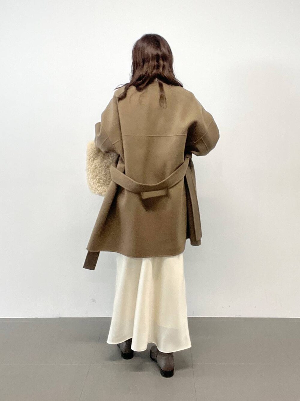 ホワイト系のハンドバッグ、ベージュ系のニット/セーター、グリーン系のピーコートを着用したレディースの秋コーディネートの5枚目の写真