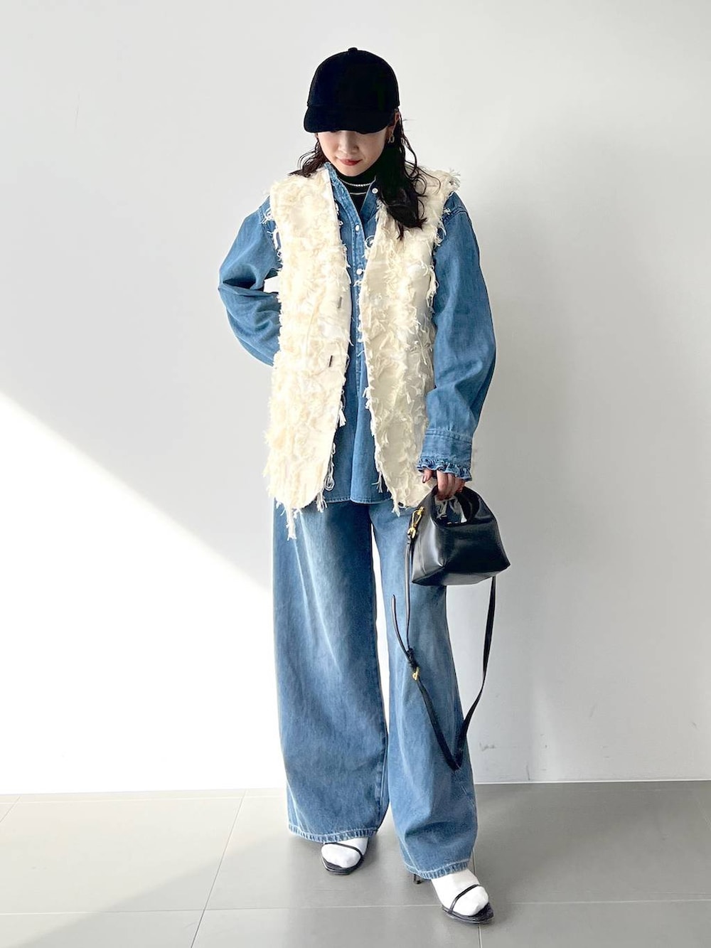 ブルー系のデニムパンツ、ブラック系のサンダル、ブラック系のTシャツ/カットソーを着用したレディースの冬コーディネートの4枚目の写真