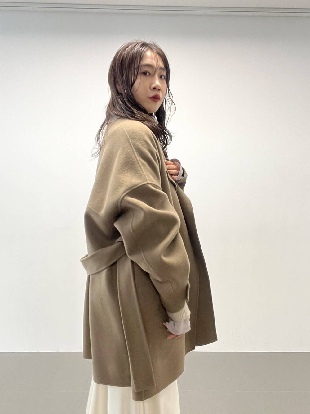 ホワイト系のハンドバッグ、ベージュ系のニット/セーター、グリーン系のピーコートを着用したレディースの秋コーディネートの7枚目の写真