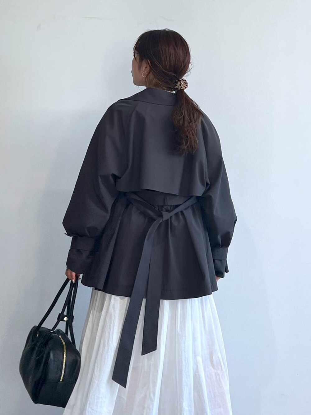 ホワイト系のスカート、グレー系のスウェット、グレー系のトレンチコートを着用したレディースの冬コーディネートの6枚目の写真