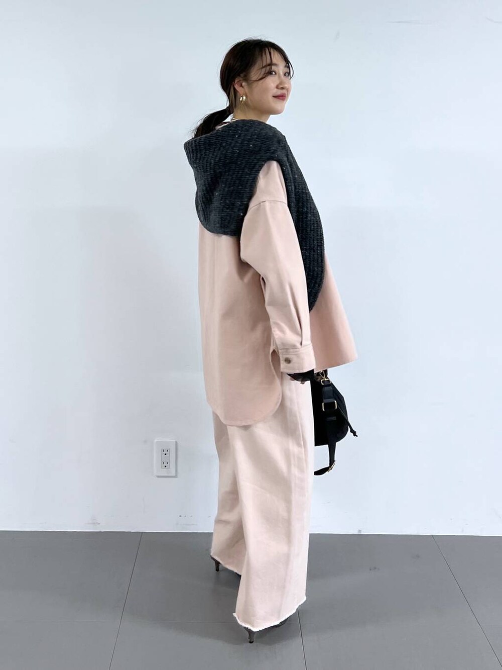 ピンク系のデニムパンツ、ベージュ系のサンダル、グレー系のニット/セーターを着用したレディースの冬コーディネートの5枚目の写真
