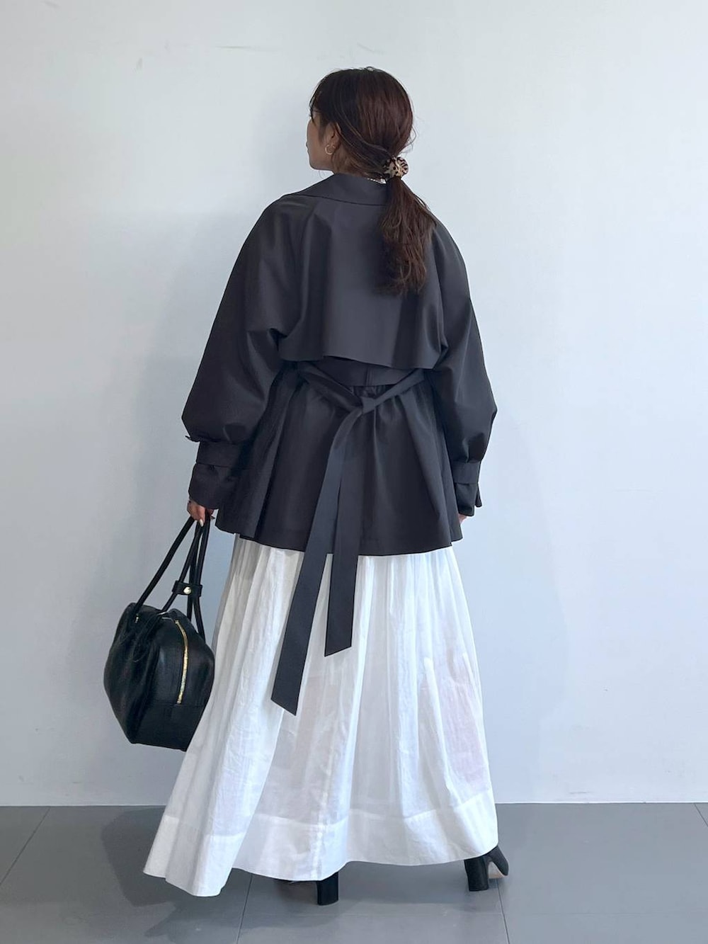 ホワイト系のスカート、グレー系のスウェット、グレー系のトレンチコートを着用したレディースの冬コーディネートの9枚目の写真