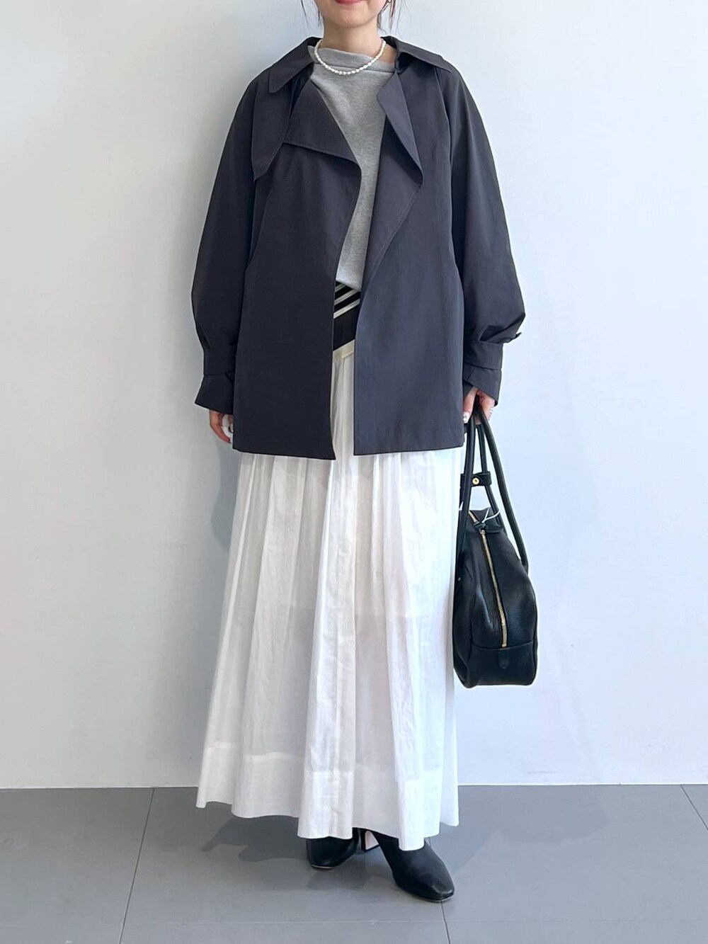 ホワイト系のスカート、グレー系のスウェット、グレー系のトレンチコートを着用したレディースの冬コーディネートの2枚目の写真