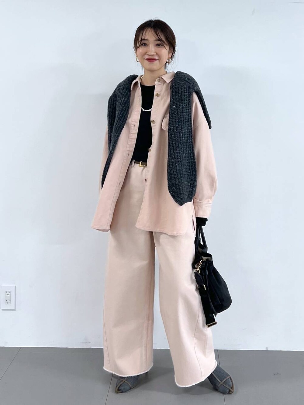 ピンク系のデニムパンツ、ベージュ系のサンダル、グレー系のニット/セーターを着用したレディースの冬コーディネートの4枚目の写真