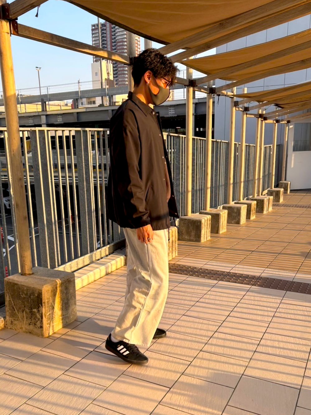 ブラック系のスニーカー、ブラック系のナイロンジャケット、グレー系のカーゴパンツを着用したメンズの春コーディネートの2枚目の写真