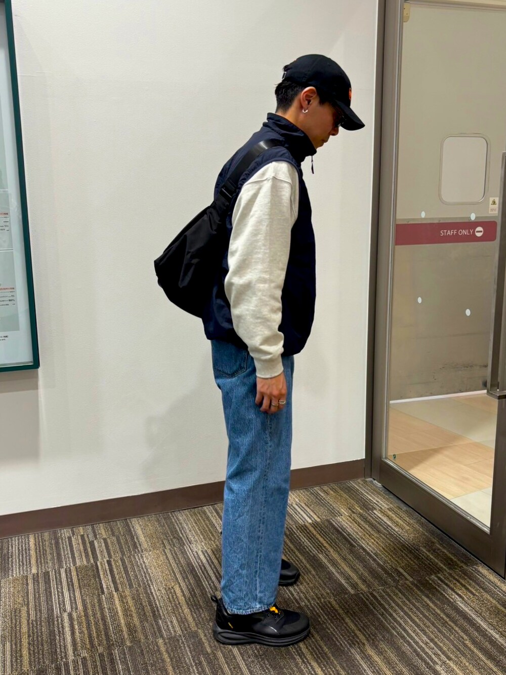 ブラック系のショルダーバッグ、ホワイト系のスウェット、ブルー系のデニムパンツを着用したメンズの春コーディネートの2枚目の写真