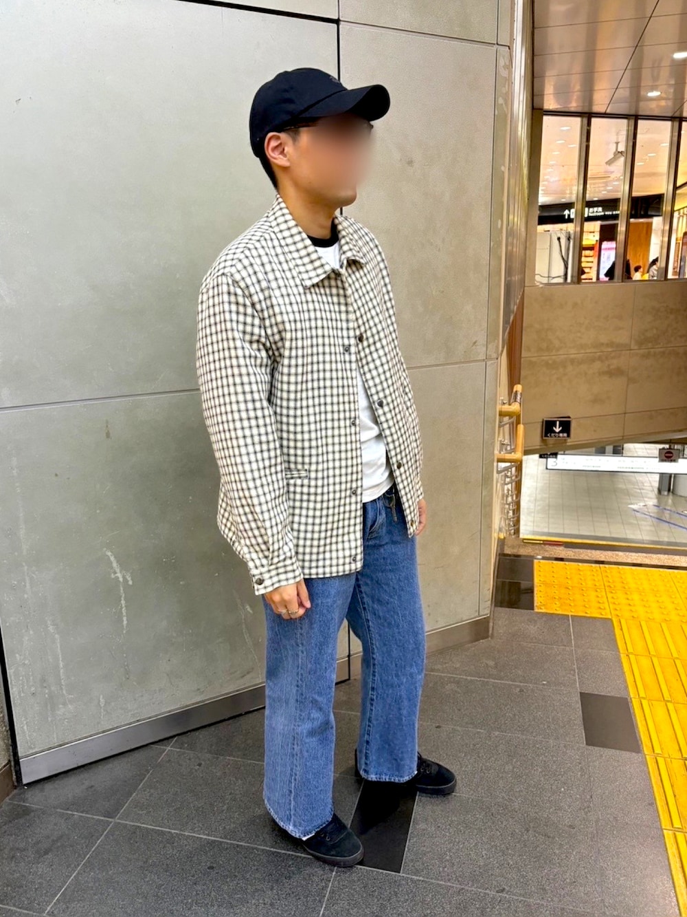 ホワイト系のブルゾン、ブラック系のスニーカー、ブルー系のデニムパンツを着用したメンズの秋コーディネートの2枚目の写真