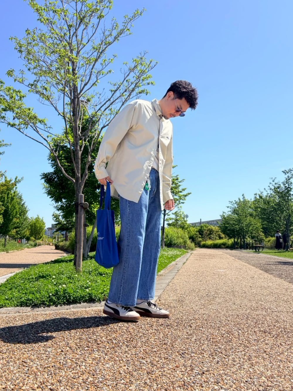 ベージュ系のシャツ/ブラウス、ブルー系のデニムパンツ、ホワイト系のスニーカーを着用したメンズの夏コーディネートの3枚目の写真