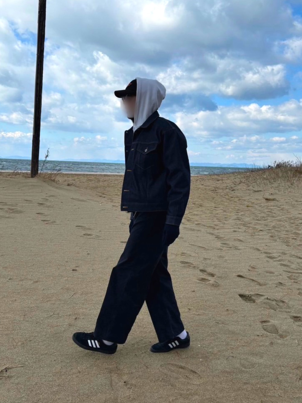 ブルー系のデニムジャケット、ブラック系のスニーカー、ホワイト系のパーカーを着用したメンズの冬コーディネートの3枚目の写真