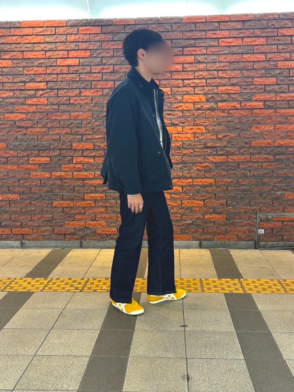 ホワイト系のスウェット、イエロー系のスリッポン、ブルー系のデニムパンツを着用したメンズの冬コーディネートの3枚目の写真