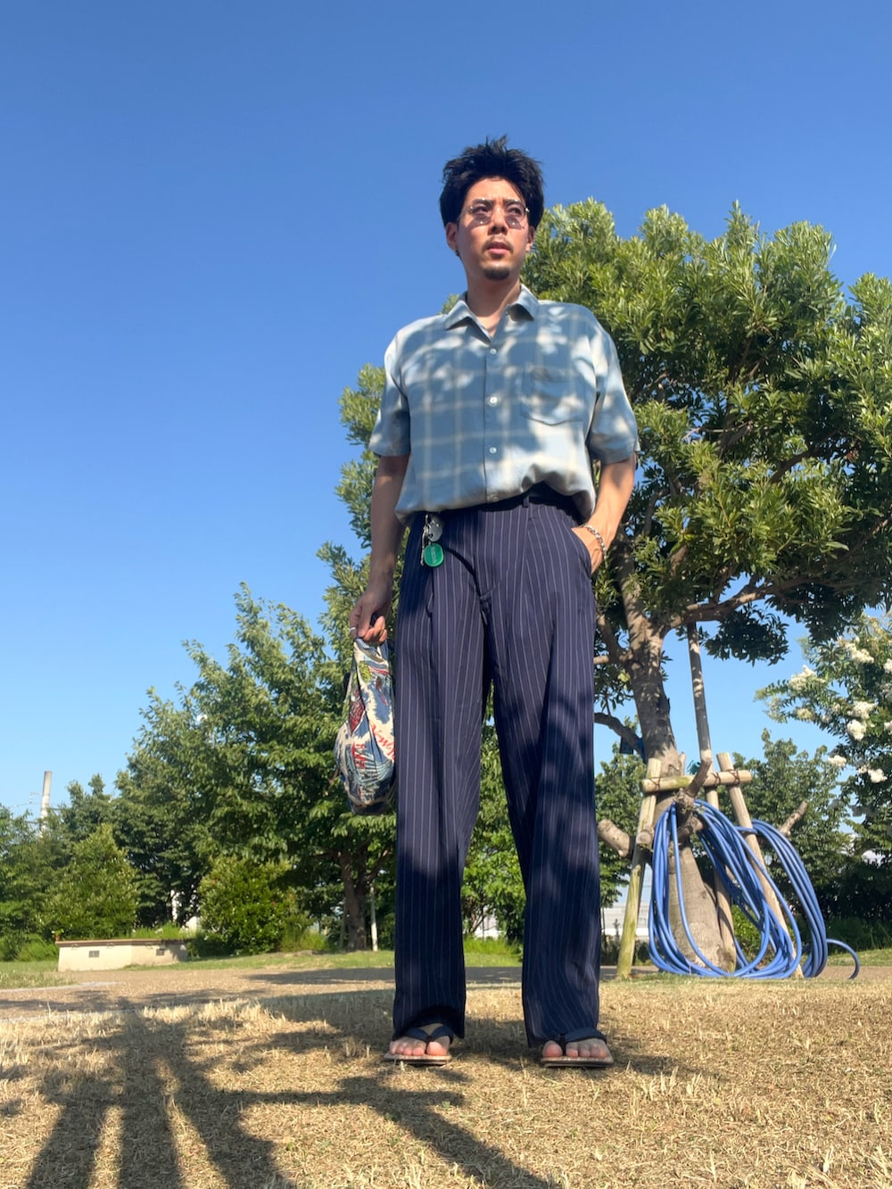 ブルー系のシャツ/ブラウス、ブルー系のスラックス、シルバー系のキーホルダーを着用したメンズの夏コーディネートの2枚目の写真