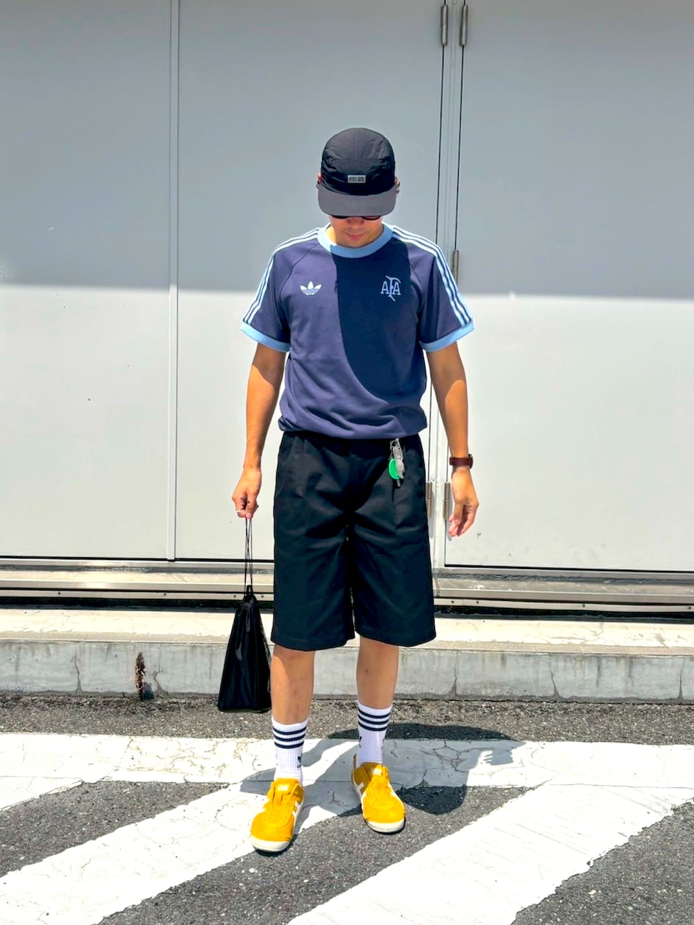 イエロー系のスリッポン、ブルー系のTシャツ/カットソー、ブラック系のパンツを着用したメンズの夏コーディネートの2枚目の写真