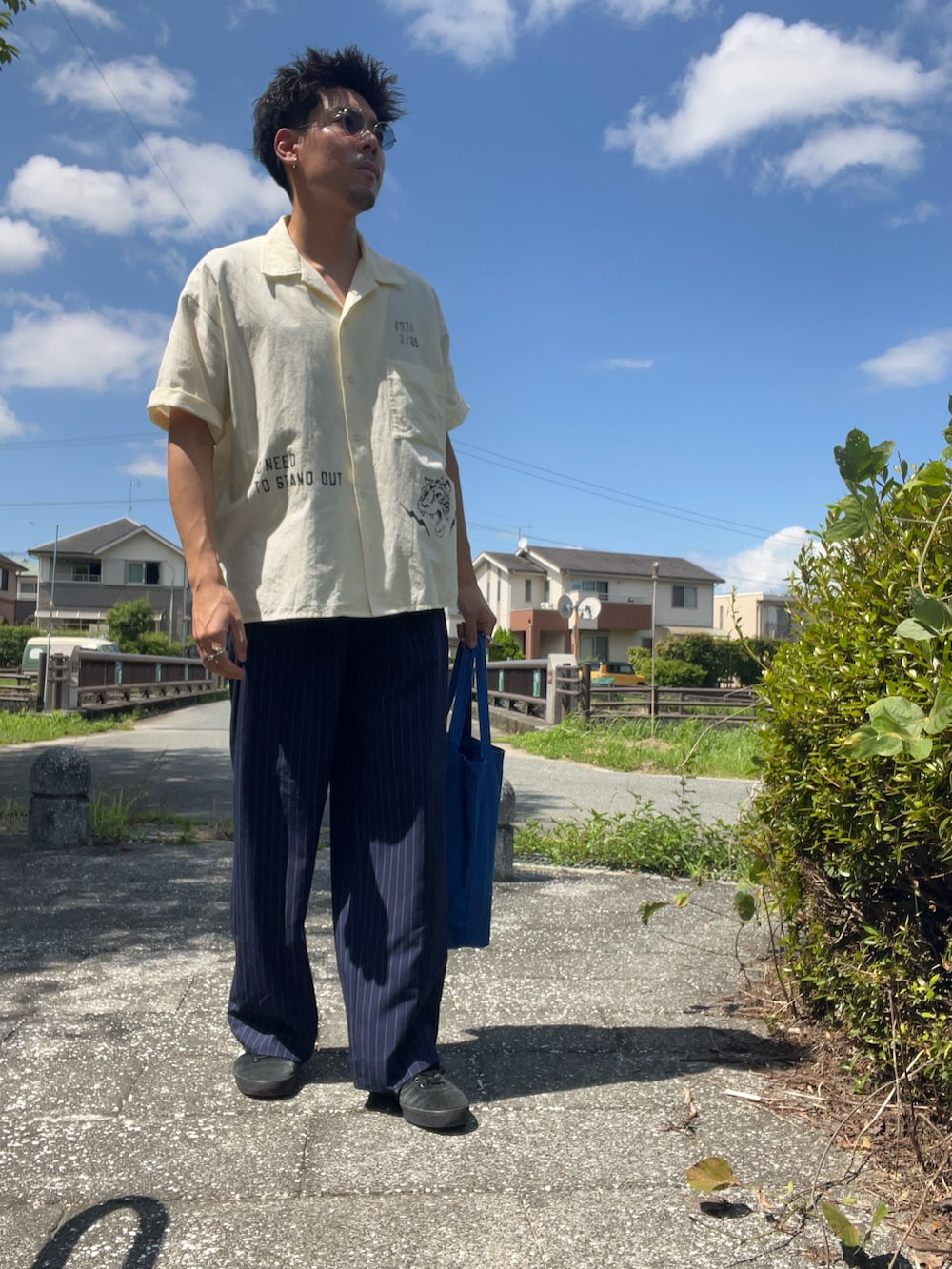 ベージュ系のシャツ/ブラウス、ブルー系のスラックスを着用したメンズの夏コーディネートの3枚目の写真