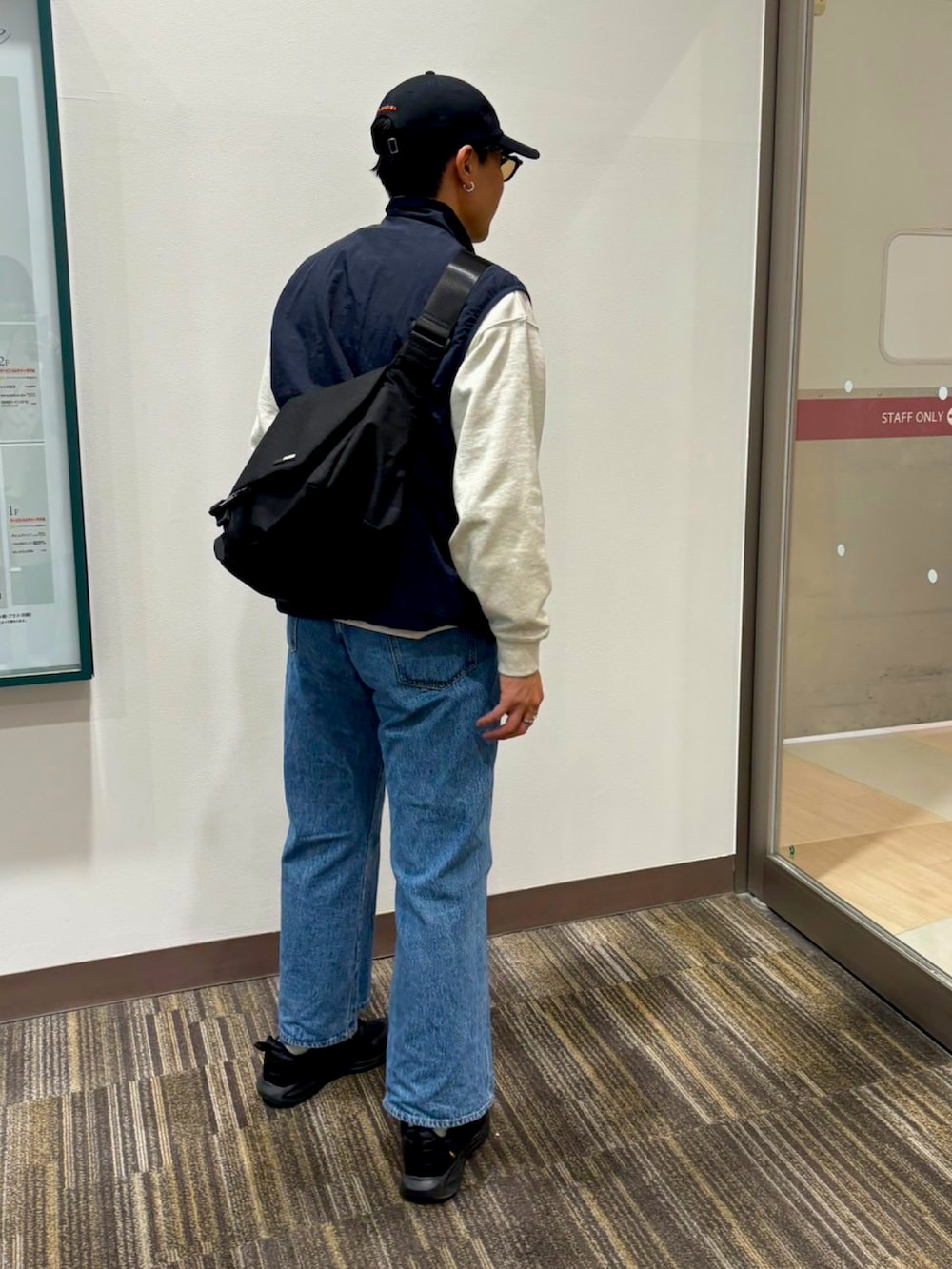 ブラック系のショルダーバッグ、ホワイト系のスウェット、ブルー系のデニムパンツを着用したメンズの春コーディネートの3枚目の写真