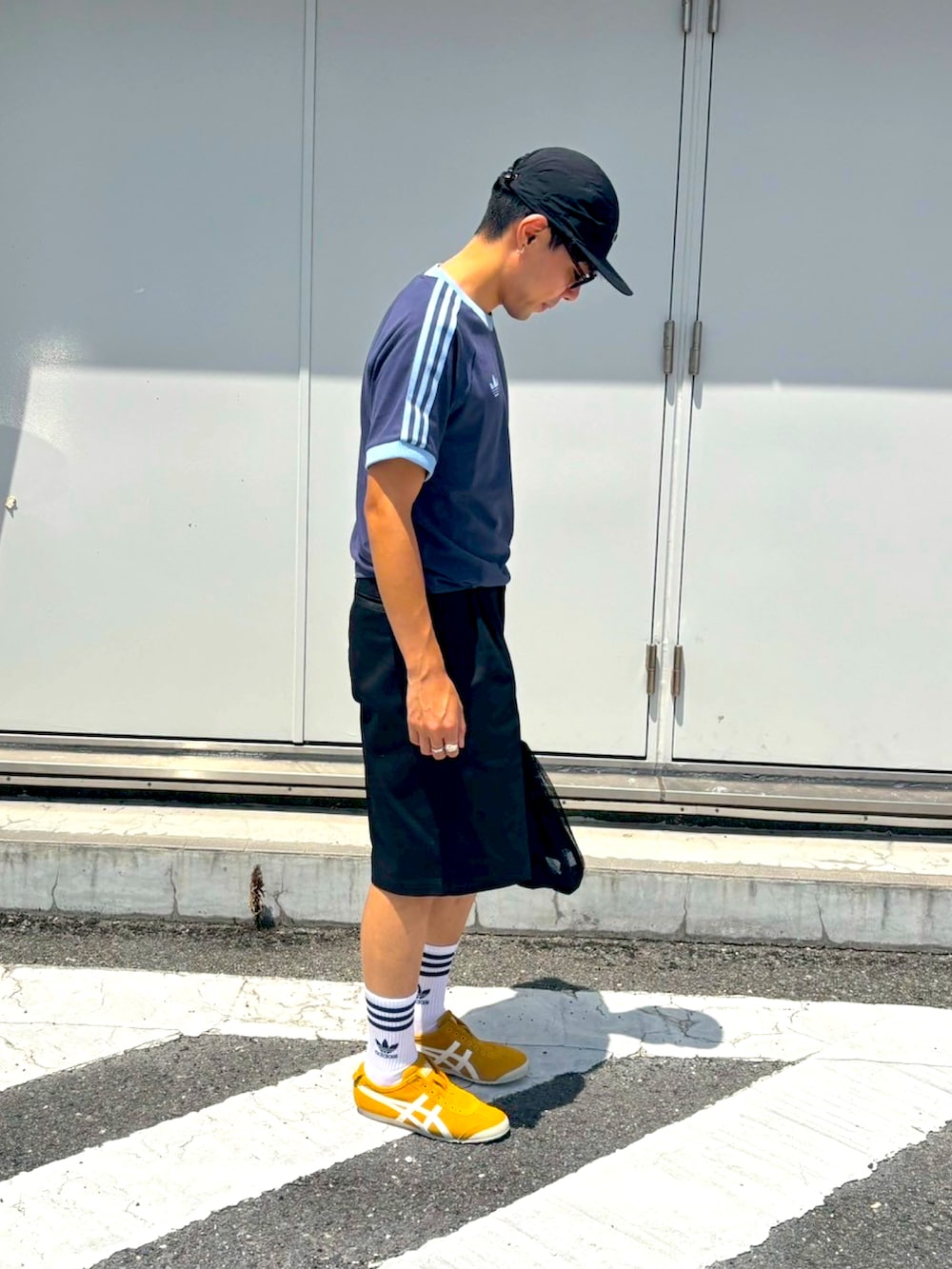 イエロー系のスリッポン、ブルー系のTシャツ/カットソー、ブラック系のパンツを着用したメンズの夏コーディネートの3枚目の写真