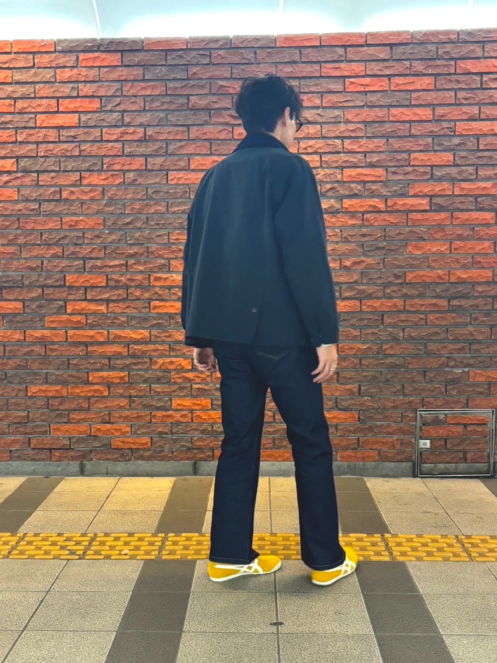 ホワイト系のスウェット、イエロー系のスリッポン、ブルー系のデニムパンツを着用したメンズの冬コーディネートの4枚目の写真