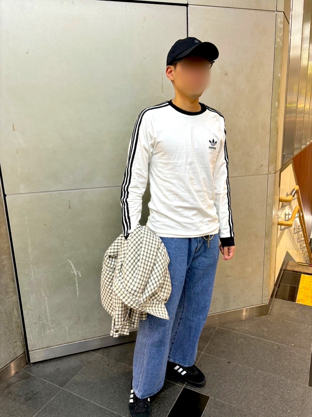 ホワイト系のブルゾン、ブラック系のスニーカー、ブルー系のデニムパンツを着用したメンズの秋コーディネートの4枚目の写真