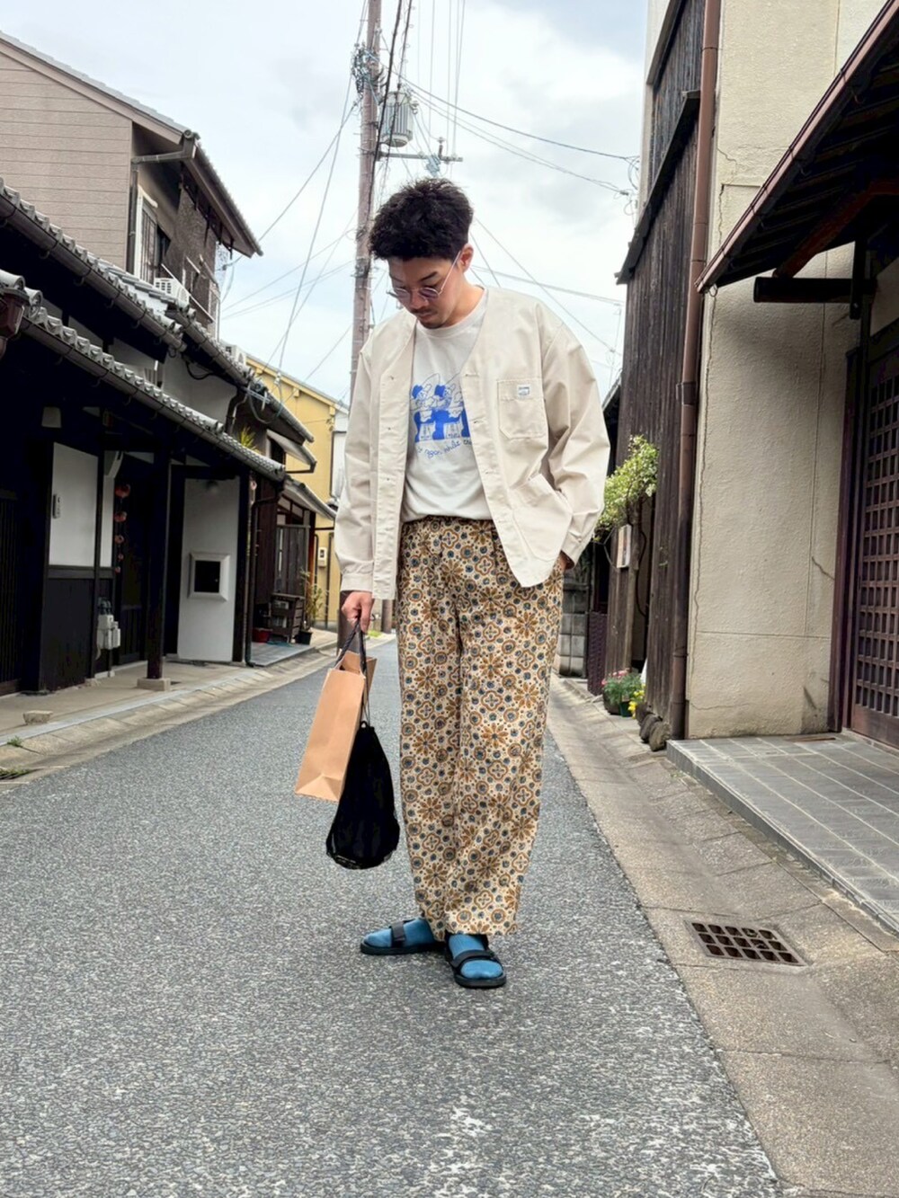 ブラック系のサンダル、ブルー系のTシャツ/カットソー、ホワイト系のノーカラージャケットを着用したメンズの春コーディネートの2枚目の写真