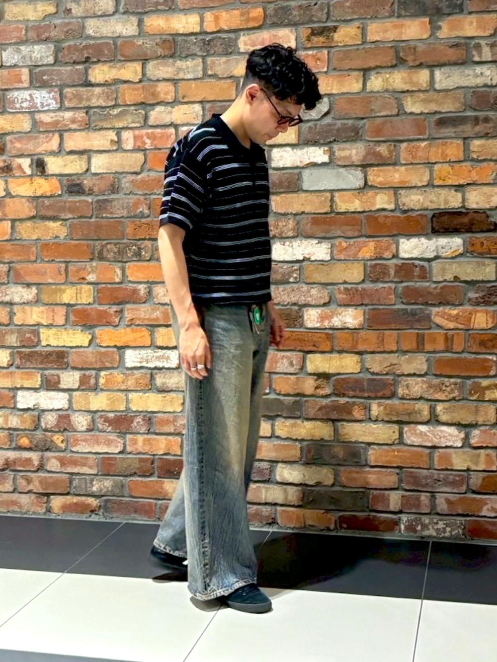 ブラック系のスニーカー、ブラック系のポロシャツ、ブルー系のデニムパンツを着用したメンズの夏コーディネートの2枚目の写真