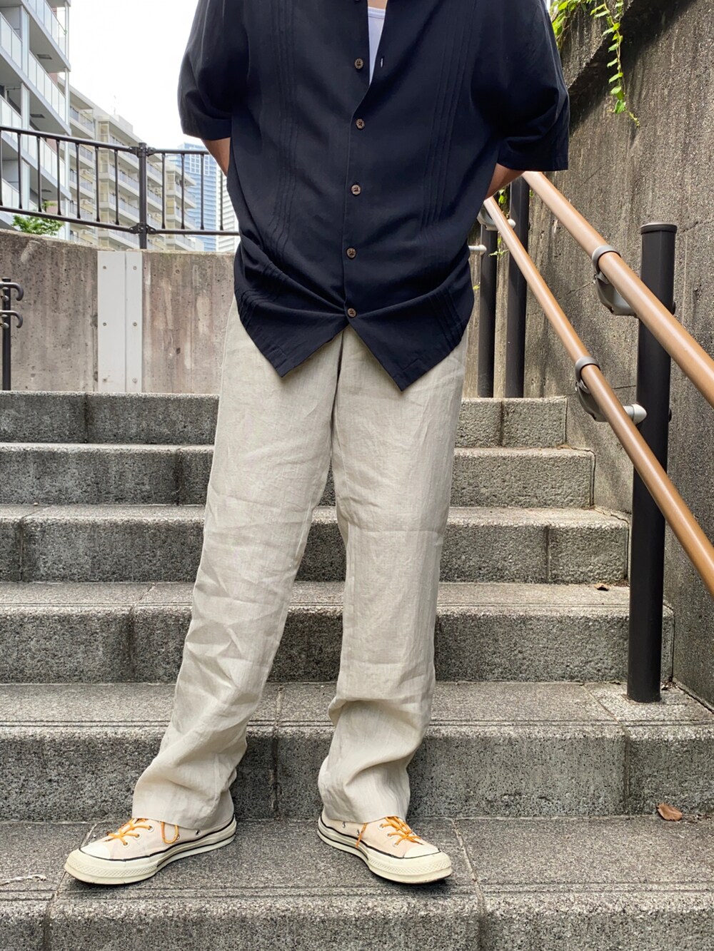 ブラック系のシャツ/ブラウス、ベージュ系のパンツ、イエロー系のスニーカーを着用したメンズの夏コーディネートの2枚目の写真