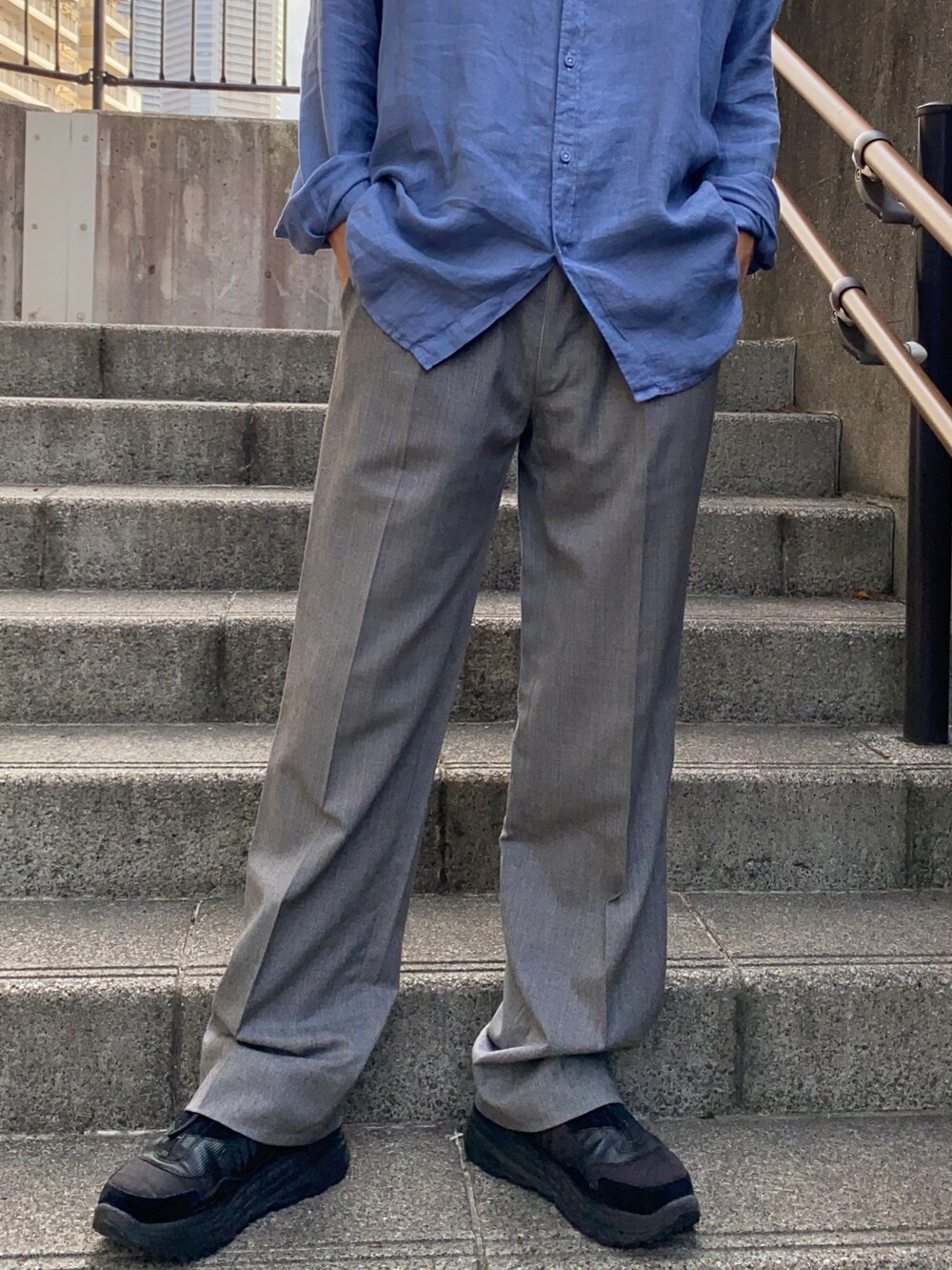 ブルー系のシャツ/ブラウス、グレー系のスラックス、ブラック系のスニーカーを着用したメンズの夏コーディネートの3枚目の写真