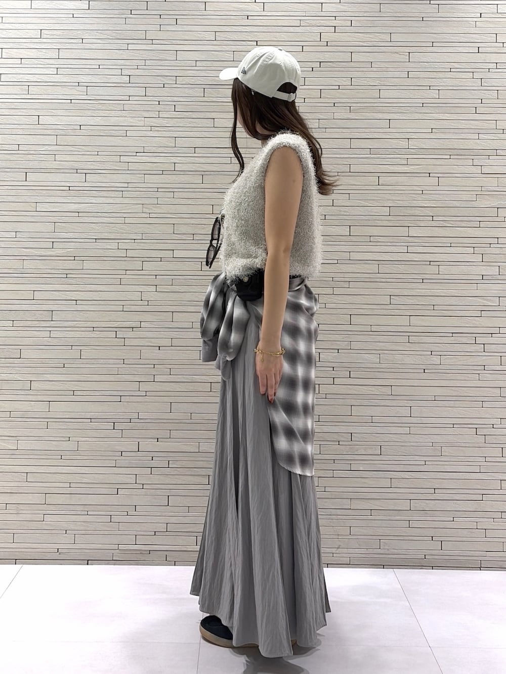 グレー系のスカート、グレー系のシャツ/ブラウス、ベージュ系のニット/セーターを着用したレディースの秋コーディネートの2枚目の写真