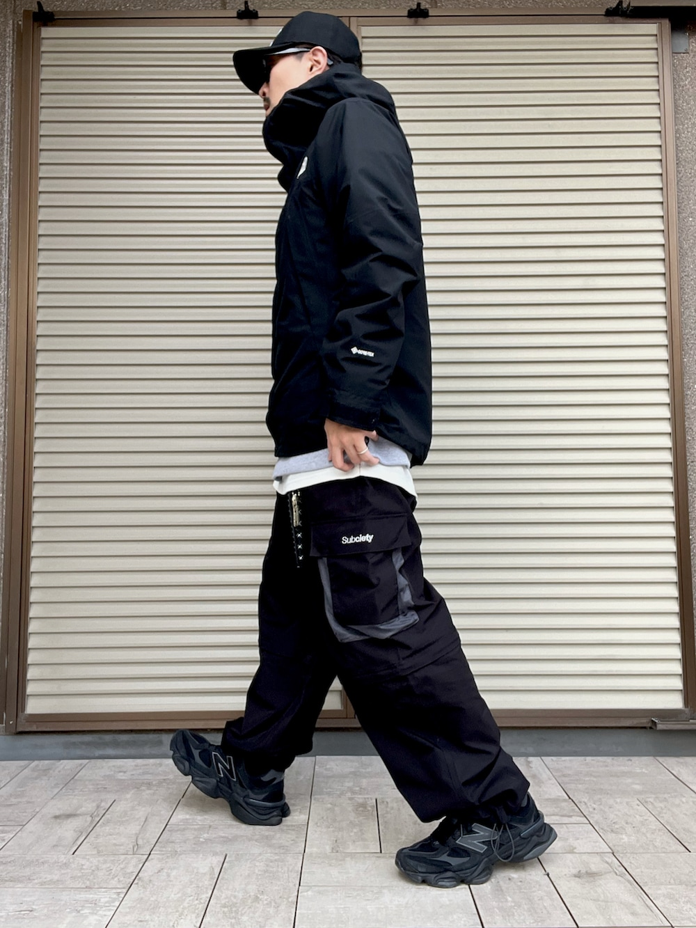 グレー系のスウェット、ブラック系のカーゴパンツ、ブラック系のマウンテンパーカーを着用したメンズの冬コーディネートの2枚目の写真