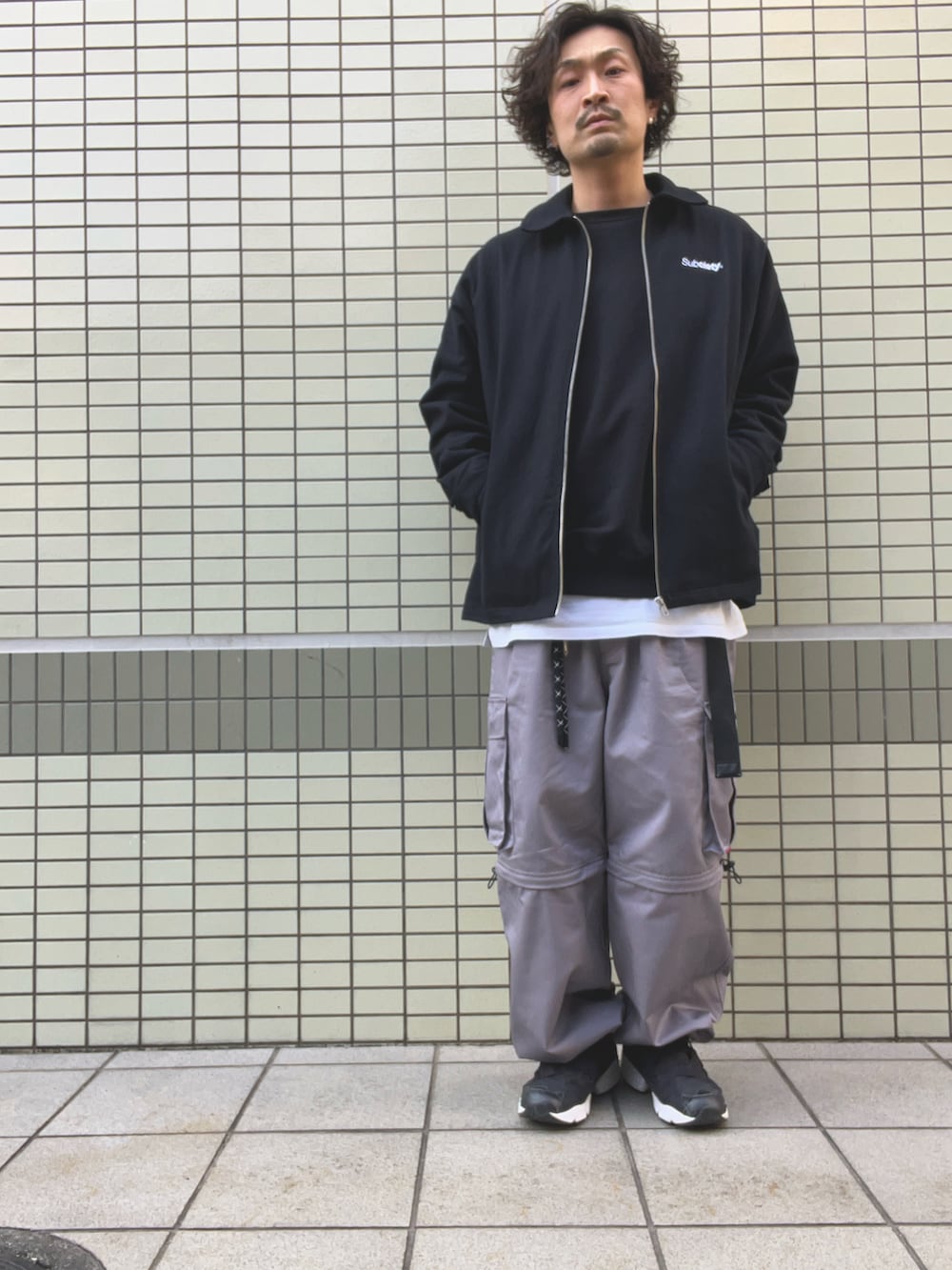 ブラック系のブルゾン、ブラック系のスウェット、ホワイト系のTシャツ/カットソーを着用したメンズの春コーディネートの2枚目の写真