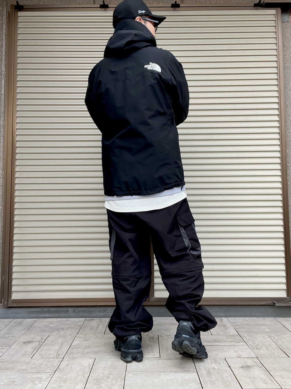 グレー系のスウェット、ブラック系のカーゴパンツ、ブラック系のマウンテンパーカーを着用したメンズの冬コーディネートの3枚目の写真