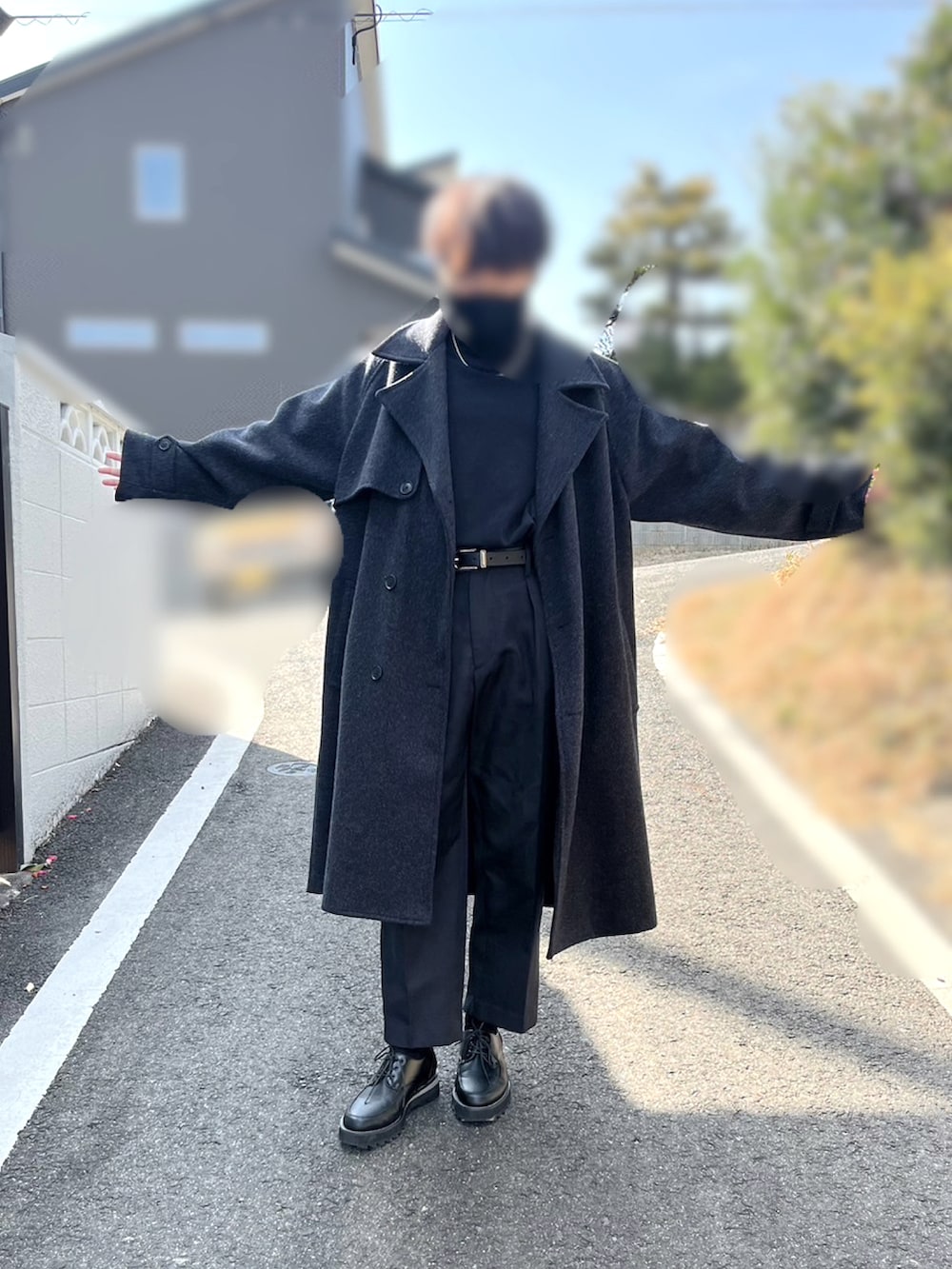 ブラック系のチェスターコート、ホワイト系のTシャツ/カットソー、ブラック系のスラックスを着用したメンズの冬コーディネートの2枚目の写真