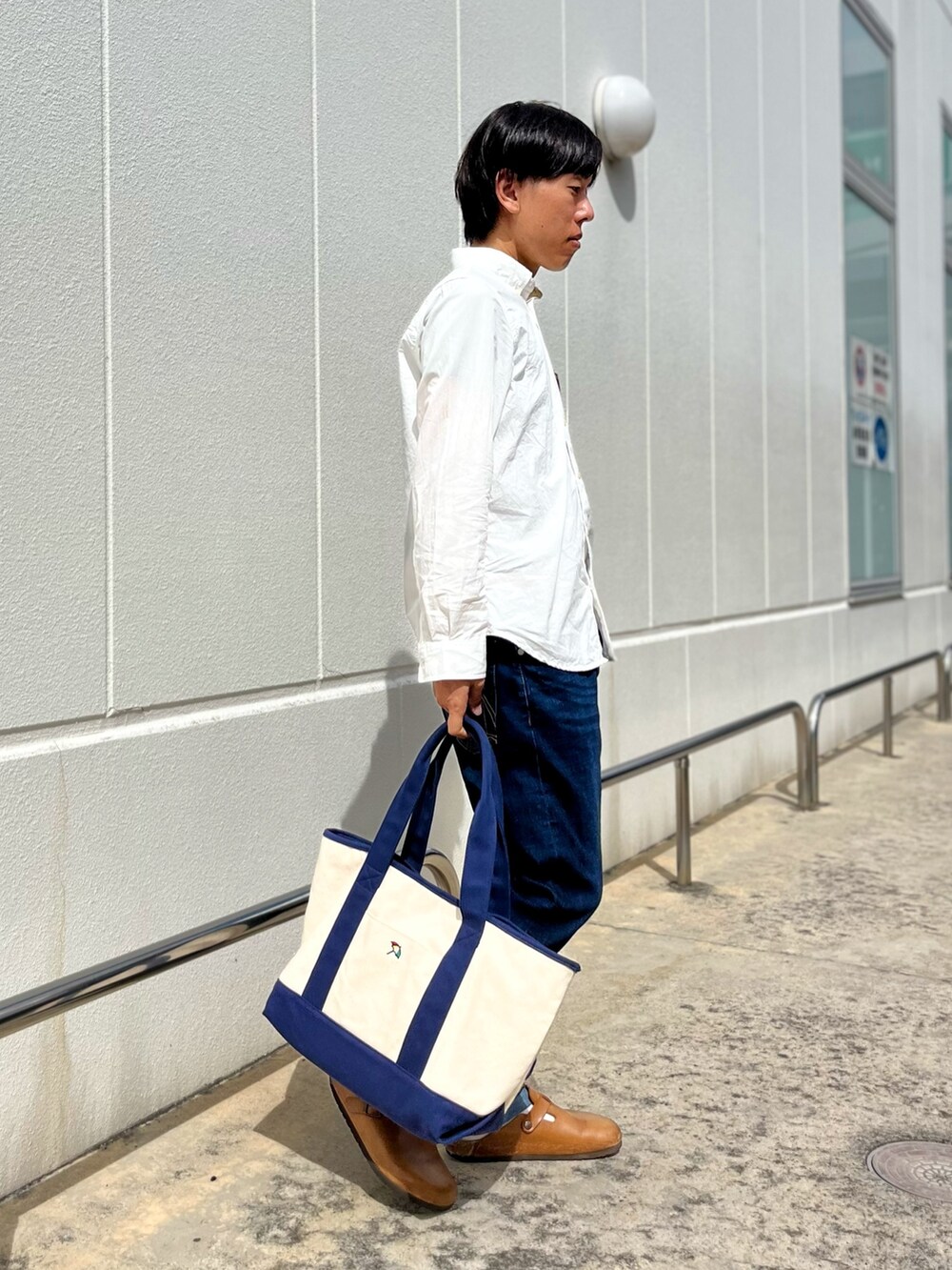 ホワイト系のシャツ/ブラウス、ブルー系のトートバッグ、ブルー系のデニムパンツを着用したメンズの秋コーディネートの3枚目の写真