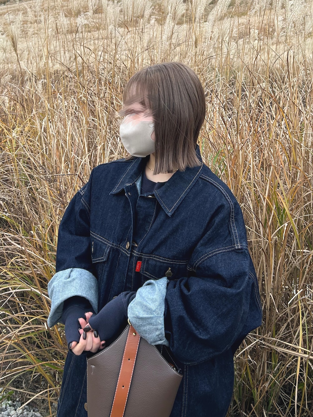 ブルー系のデニムジャケット、ブラック系のスカート、ブラック系のブーツを着用したレディースの冬コーディネートの2枚目の写真