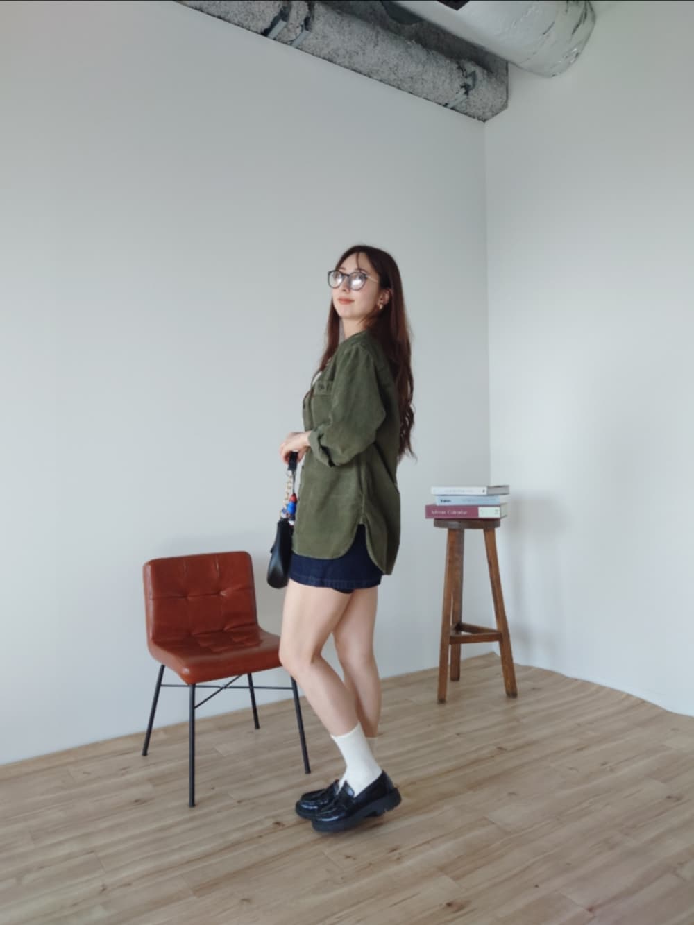 ブラック系のショルダーバッグ、ブルー系のその他パンツ、グリーン系のノーカラージャケットを着用したレディースの秋コーディネートの2枚目の写真