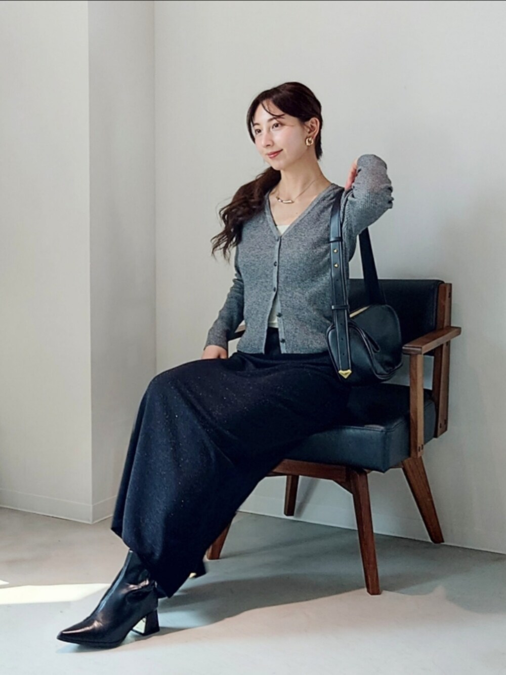 ブラック系のショルダーバッグ、グレー系のカーディガン/ボレロ、ブラック系のスカートを着用したレディースの秋コーディネートの3枚目の写真